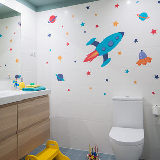 Modelo de cuarto de baño infantil, contemporáneo, pequeño, con armarios con paneles lisos, puertas de armario de madera clara, sanitario de dos piezas, baldosas y/o azulejos blancos, baldosas y/o azulejos de cerámica, paredes blancas, suelo de baldosas de cerámica, lavabo integrado, encimera de acrílico y suelo azul