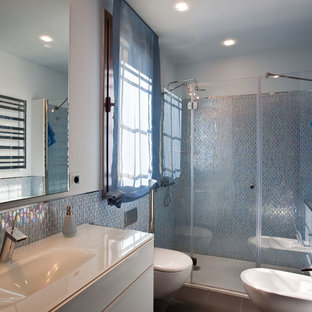 Diseño de cuarto de baño con ducha, contemporáneo, con armarios con paneles lisos, puertas de armario blancas, ducha empotrada, sanitario de pared, baldosas y/o azulejos azules, paredes azules, lavabo tipo consola, suelo gris y ducha con puerta con bisagras