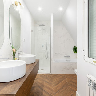 Diseño de cuarto de baño actual con armarios con paneles lisos, puertas de armario de madera oscura, bañera empotrada, ducha empotrada, baldosas y/o azulejos blancos, suelo de madera en tonos medios, lavabo sobreencimera, encimera de madera, suelo marrón, ducha con puerta con bisagras y encimeras marrones