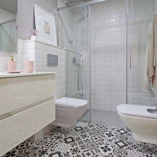 Modelo de cuarto de baño con ducha, contemporáneo, de tamaño medio, con ducha a ras de suelo, sanitario de pared, baldosas y/o azulejos blancos, baldosas y/o azulejos de cemento, paredes grises, suelo con mosaicos de baldosas, lavabo integrado, ducha con puerta corredera, armarios con paneles lisos, puertas de armario blancas y encimeras blancas