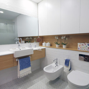 Ejemplo de cuarto de baño principal, actual, de tamaño medio, con armarios con paneles lisos, ducha a ras de suelo, sanitario de pared, baldosas y/o azulejos blancos, baldosas y/o azulejos de cemento, paredes blancas, suelo de baldosas de cerámica, lavabo sobreencimera, puertas de armario de madera oscura, suelo blanco y encimeras blancas