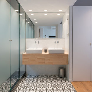 Diseño de cuarto de baño principal, actual, de tamaño medio, con armarios con paneles lisos, puertas de armario beige, ducha empotrada, paredes blancas, lavabo sobreencimera, encimera de madera, suelo multicolor, ducha con puerta con bisagras y encimeras beige