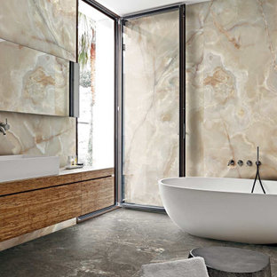 Imagen de cuarto de baño principal, actual, grande, con suelo de baldosas de cerámica, armarios con paneles lisos, puertas de armario de madera oscura, bañera exenta, baldosas y/o azulejos beige, lavabo sobreencimera, suelo gris y encimeras marrones