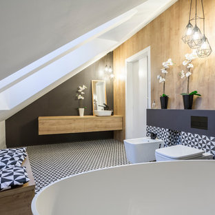 Foto de cuarto de baño azulejo de dos tonos, contemporáneo, con armarios con paneles lisos, puertas de armario de madera oscura, bañera exenta, bidé, baldosas y/o azulejos negros, paredes negras, lavabo sobreencimera, encimera de madera, suelo multicolor y encimeras marrones