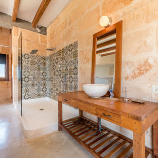 Imagen de cuarto de baño principal, mediterráneo, con armarios abiertos, puertas de armario de madera oscura, ducha abierta, paredes rosas, lavabo sobreencimera, encimera de madera, suelo beige y ducha abierta