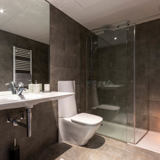 Ejemplo de cuarto de baño único, contemporáneo, de tamaño medio, con ducha esquinera, sanitario de una pieza, baldosas y/o azulejos grises, baldosas y/o azulejos de porcelana, suelo de baldosas de porcelana, lavabo suspendido, suelo gris y ducha con puerta con bisagras