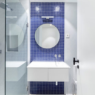 Ejemplo de cuarto de baño con ducha, actual, pequeño, con armarios con paneles lisos, puertas de armario blancas, baldosas y/o azulejos azules, baldosas y/o azulejos en mosaico, lavabo integrado y encimeras blancas