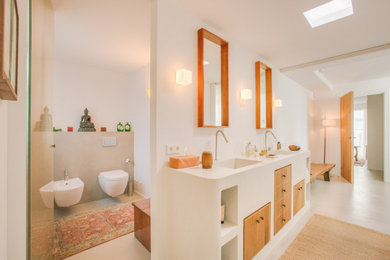 Modernes Badezimmer mit flächenbündigen Schrankfronten, hellbraunen Holzschränken, Wandtoilette, weißer Wandfarbe, integriertem Waschbecken und grauem Boden in Sonstige