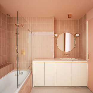 Ejemplo de cuarto de baño con ducha, actual, con armarios con paneles lisos, bañera encastrada, combinación de ducha y bañera, baldosas y/o azulejos rosa, paredes rosas, lavabo integrado, suelo gris, ducha abierta y encimeras blancas