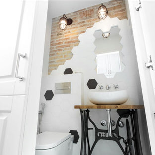 Design ideas for a small industrial bathroom in Barcelona with shaker cabinets, white cabinets, a wall-mount toilet, black and white tile, a console sink, wood benchtops, a single vanity, a built-in vanity and brick walls.