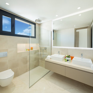 Foto de cuarto de baño principal, contemporáneo, con puertas de armario beige, ducha a ras de suelo, baldosas y/o azulejos beige, paredes beige, lavabo sobreencimera, suelo beige, encimeras beige, armarios con paneles lisos y sanitario de pared