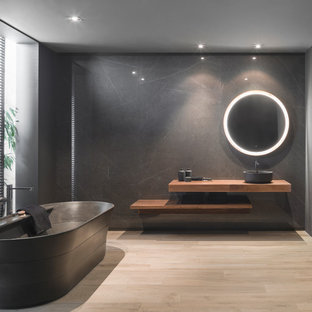 Foto de cuarto de baño principal, minimalista, con bañera exenta, paredes negras, suelo de madera clara, lavabo sobreencimera, suelo beige, armarios abiertos, puertas de armario de madera oscura, encimera de madera y encimeras marrones