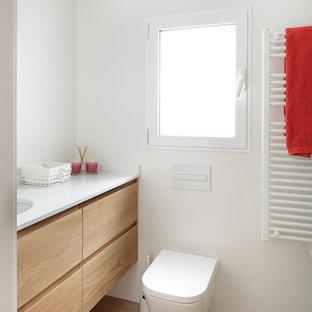 Ejemplo de cuarto de baño con ducha, minimalista, con armarios tipo mueble, puertas de armario de madera oscura, baldosas y/o azulejos blancos, encimeras blancas, sanitario de pared, paredes blancas, suelo de madera en tonos medios, lavabo bajoencimera y suelo beige
