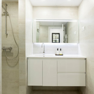 Modelo de cuarto de baño con ducha, actual, con puertas de armario blancas, baldosas y/o azulejos beige, ducha abierta, encimeras blancas, armarios con paneles lisos, paredes beige, lavabo integrado y suelo beige
