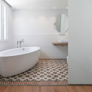 Foto de cuarto de baño principal, actual, de tamaño medio, con armarios abiertos, bañera exenta, baldosas y/o azulejos blancos, baldosas y/o azulejos de porcelana, paredes blancas, lavabo sobreencimera, encimera de madera, suelo multicolor y encimeras beige