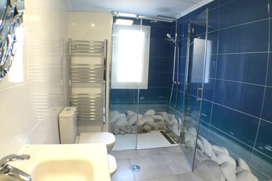 Diseño de cuarto de baño costero de tamaño medio con ducha a ras de suelo, sanitario de dos piezas, paredes multicolor, suelo de baldosas de cerámica, aseo y ducha y lavabo integrado