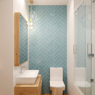 Imagen de cuarto de baño con ducha, escandinavo, pequeño, con puertas de armario de madera clara, baldosas y/o azulejos azules, baldosas y/o azulejos de cerámica, paredes blancas, encimera de madera, ducha con puerta corredera, armarios con paneles lisos, bañera empotrada, combinación de ducha y bañera, sanitario de una pieza, suelo de madera en tonos medios, lavabo sobreencimera, suelo beige y encimeras beige