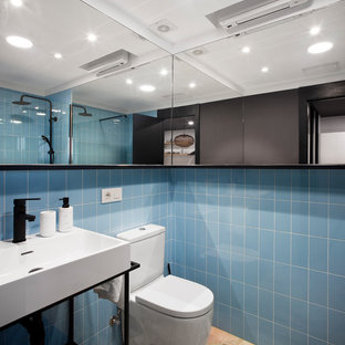 Diseño de cuarto de baño con ducha, actual, con armarios abiertos, puertas de armario negras, ducha a ras de suelo, baldosas y/o azulejos azules, paredes azules, ducha abierta, sanitario de una pieza, lavabo tipo consola y suelo beige