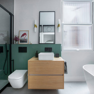 Ejemplo de cuarto de baño principal, único, flotante y panelado, panelado, con armarios con paneles lisos, puertas de armario de madera oscura, bañera exenta, ducha empotrada, sanitario de pared, baldosas y/o azulejos grises, paredes blancas, lavabo sobreencimera, encimera de madera, suelo gris, encimeras marrones y panelado