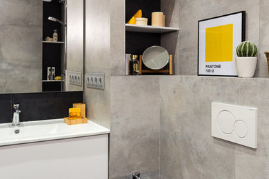 Imagen de cuarto de baño contemporáneo con armarios con paneles lisos, puertas de armario blancas, sanitario de pared, baldosas y/o azulejos grises, aseo y ducha, lavabo integrado y suelo negro