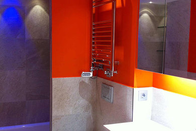 Imagen de cuarto de baño principal actual de tamaño medio con armarios con paneles lisos, puertas de armario grises, bañera empotrada, combinación de ducha y bañera, sanitario de pared, paredes rojas y lavabo suspendido