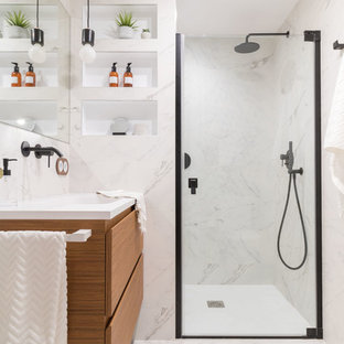 Modelo de cuarto de baño con ducha, actual, con puertas de armario de madera oscura, lavabo integrado, armarios con paneles lisos, ducha empotrada, baldosas y/o azulejos blancos, baldosas y/o azulejos de mármol, paredes blancas, suelo de mármol, suelo blanco, ducha con puerta con bisagras y encimeras blancas
