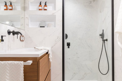 Idéer för funkis vitt badrum med dusch, med skåp i mellenmörkt trä, ett integrerad handfat, släta luckor, en dusch i en alkov, vit kakel, marmorkakel, vita väggar, marmorgolv, vitt golv och dusch med gångjärnsdörr