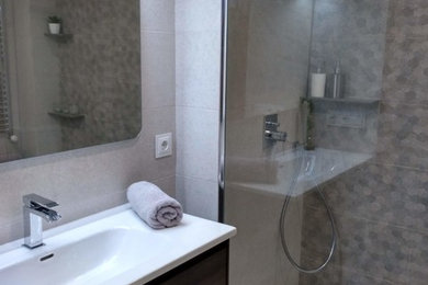 Diseño de cuarto de baño principal minimalista de tamaño medio con puertas de armario de madera en tonos medios, ducha a ras de suelo, sanitario de una pieza, baldosas y/o azulejos grises, baldosas y/o azulejos de porcelana, paredes grises, lavabo integrado, suelo gris y encimeras blancas