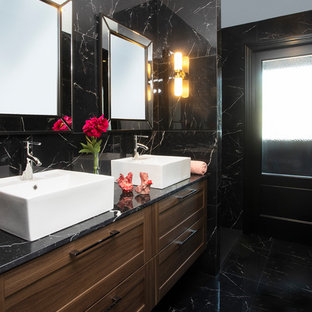 Ejemplo de cuarto de baño principal, tradicional renovado, con puertas de armario de madera en tonos medios, baldosas y/o azulejos negros, lavabo sobreencimera, suelo negro, armarios con paneles empotrados, paredes negras y encimeras negras