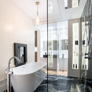 Imagen de cuarto de baño principal, contemporáneo, con armarios con paneles lisos, puertas de armario blancas, bañera exenta, ducha a ras de suelo, paredes beige, suelo de mármol, lavabo sobreencimera, suelo negro y encimeras blancas