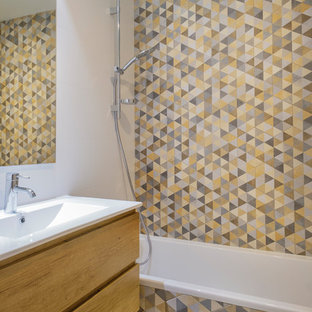 Photo of a contemporary master bathroom in Other with flat-panel cabinets, light wood cabinets, an alcove tub, a shower/bathtub combo, gray tile, yellow tile, white walls, mosaic tile floors, an integrated sink, multi-coloured floor and white benchtops.