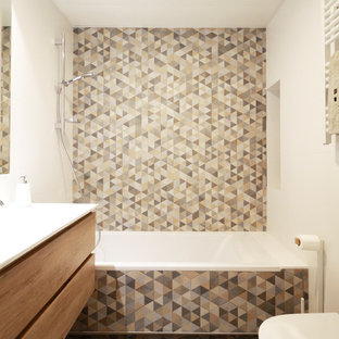 Modelo de cuarto de baño actual, pequeño, con armarios con paneles lisos, puertas de armario de madera oscura, bañera empotrada, combinación de ducha y bañera, baldosas y/o azulejos multicolor, baldosas y/o azulejos de cerámica, paredes blancas, suelo multicolor, sanitario de pared, suelo de baldosas de cerámica, encimeras blancas y lavabo bajoencimera