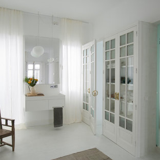 Modelo de cuarto de baño principal, contemporáneo, con armarios con paneles lisos, puertas de armario blancas, ducha empotrada, paredes blancas, lavabo suspendido, suelo blanco y ducha abierta