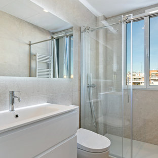 Modelo de cuarto de baño con ducha, actual, de tamaño medio, con armarios con paneles lisos, puertas de armario blancas, ducha empotrada, sanitario de una pieza, baldosas y/o azulejos grises, lavabo integrado, suelo beige, ducha con puerta con bisagras y encimeras blancas