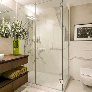 Diseño de cuarto de baño con ducha, minimalista, con armarios abiertos, puertas de armario de madera en tonos medios, ducha esquinera, sanitario de pared, baldosas y/o azulejos blancos, paredes grises, lavabo sobreencimera, encimera de madera, suelo gris, ducha con puerta con bisagras y encimeras marrones