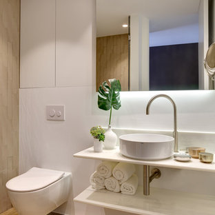 Foto de cuarto de baño con ducha, costero, con puertas de armario blancas, suelo de madera en tonos medios, lavabo sobreencimera, encimera de mármol, encimeras blancas, ducha empotrada, sanitario de pared, paredes blancas, suelo beige y ducha con puerta con bisagras