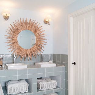 Foto de cuarto de baño mediterráneo con baldosas y/o azulejos de cerámica, armarios abiertos, baldosas y/o azulejos grises, paredes azules, lavabo sobreencimera, encimera de azulejos, suelo turquesa y encimeras grises