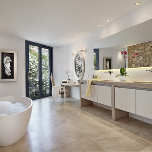 Foto de cuarto de baño principal, actual, grande, con bañera exenta, paredes blancas, suelo de piedra caliza, lavabo integrado, encimera de piedra caliza, suelo beige, encimeras beige, armarios con paneles lisos, puertas de armario blancas, baldosas y/o azulejos beige y baldosas y/o azulejos de piedra