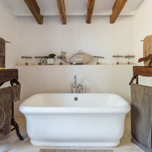 Diseño de cuarto de baño mediterráneo con bañera exenta, paredes blancas y suelo beige