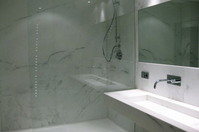 Diseño de cuarto de baño contemporáneo con ducha a ras de suelo, paredes blancas, suelo de baldosas de porcelana, lavabo suspendido y encimera de mármol
