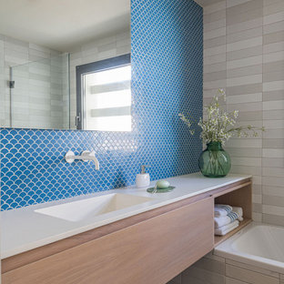 Ejemplo de cuarto de baño infantil, único y flotante, mediterráneo, de tamaño medio, con puertas de armario de madera clara, bañera empotrada, baldosas y/o azulejos azules, suelo de madera clara, encimeras blancas, armarios con paneles lisos, baldosas y/o azulejos en mosaico, lavabo integrado y suelo beige