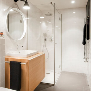 Ejemplo de cuarto de baño con ducha, contemporáneo, de tamaño medio, con armarios con paneles lisos, puertas de armario de madera clara, ducha esquinera, sanitario de pared, baldosas y/o azulejos blancos, suelo de baldosas de porcelana, lavabo sobreencimera, encimera de madera, suelo gris, ducha con puerta con bisagras y encimeras beige