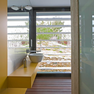 Ejemplo de cuarto de baño con ducha, único y flotante, actual, de tamaño medio, con puertas de armario amarillas, paredes amarillas, lavabo sobreencimera, suelo marrón y encimeras amarillas