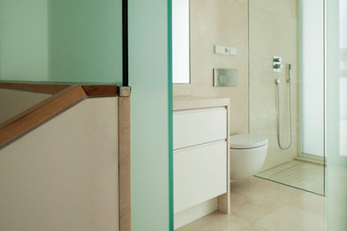 Imagen de cuarto de baño actual de tamaño medio con armarios con paneles lisos, puertas de armario blancas, ducha a ras de suelo, sanitario de pared, paredes beige, aseo y ducha y lavabo integrado