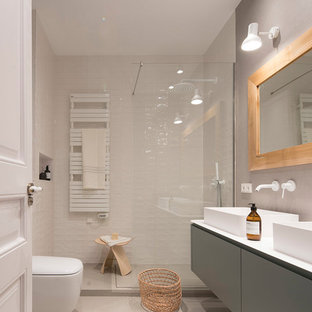 Foto de cuarto de baño contemporáneo, de tamaño medio, con armarios tipo mueble, puertas de armario grises, sanitario de pared, baldosas y/o azulejos beige, baldosas y/o azulejos de cerámica, paredes beige, suelo de cemento, lavabo sobreencimera, encimera de laminado, suelo beige y encimeras blancas