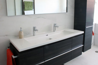 Design ideas for a large modern ensuite bathroom in Madrid with freestanding cabinets, dark wood cabinets, a corner bath, a walk-in shower, a one-piece toilet, white tiles, porcelain tiles, white walls, porcelain flooring, an integrated sink and white floors.