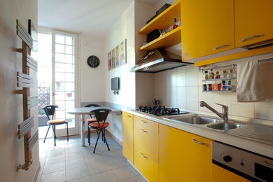 Immagine di una cucina contemporanea di medie dimensioni con lavello da incasso, ante lisce, ante gialle, top in laminato, paraspruzzi beige, elettrodomestici neri, pavimento in gres porcellanato, penisola e pavimento beige