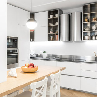 Ispirazione per un cucina con isola centrale minimal con ante lisce, ante bianche, pavimento in legno massello medio, pavimento marrone e top grigio