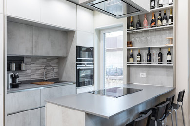 Idee per una cucina parallela contemporanea con lavello sottopiano, ante lisce, ante grigie, paraspruzzi grigio, elettrodomestici neri e top grigio