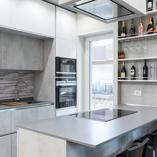 Idee per una cucina parallela contemporanea con lavello sottopiano, ante lisce, ante grigie, paraspruzzi grigio, elettrodomestici neri e top grigio